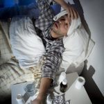 Man lying in bed with headache and fever